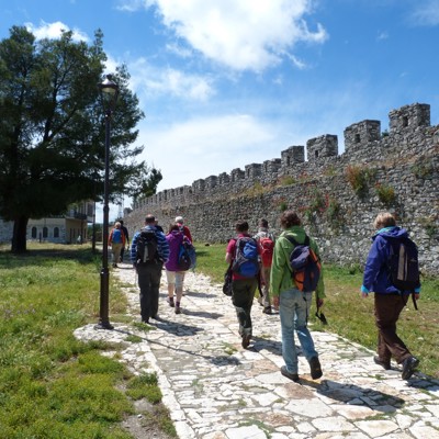Wandelaars tijdens groepsrondreis Albanië bij een oude stadsmuur op een zonnig pad.
