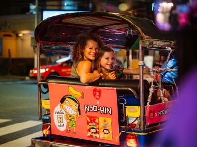 Moeder en kind in een tuk-tuk tijdens een avondrit door Bangkok, Thailand.