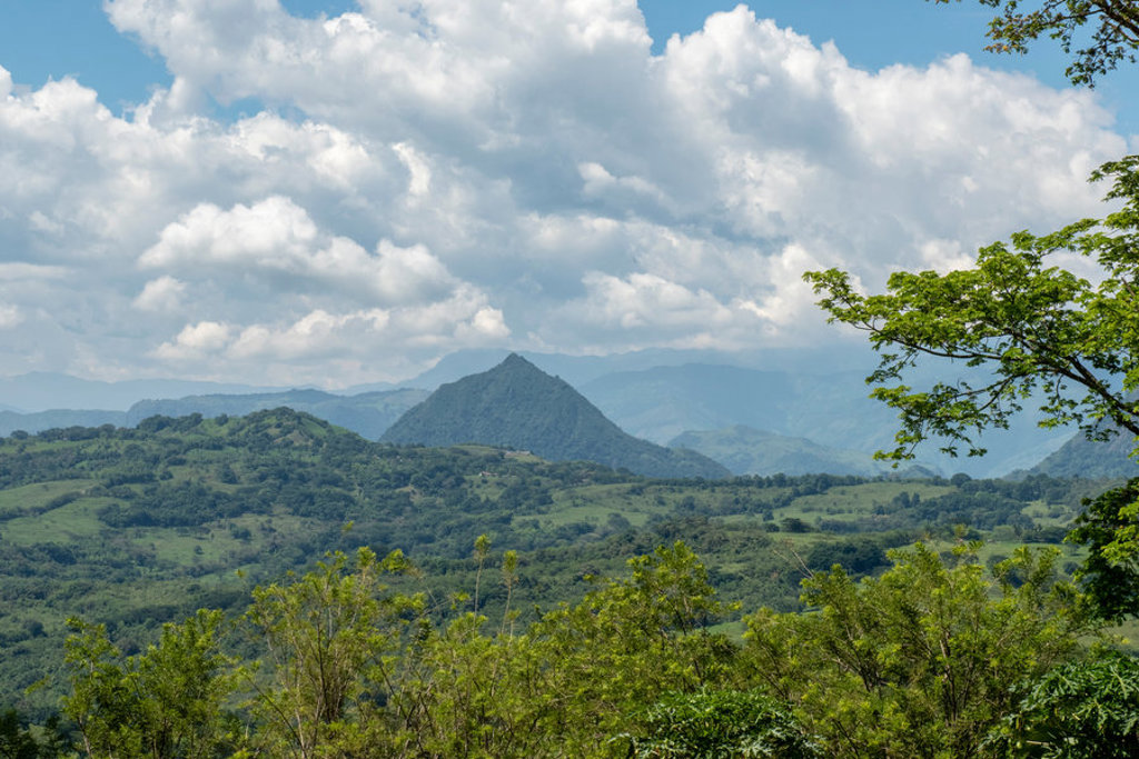 Groene heuvels en bergen in Colombia onder een blauwe lucht met wolken, tijdens een familiereis.