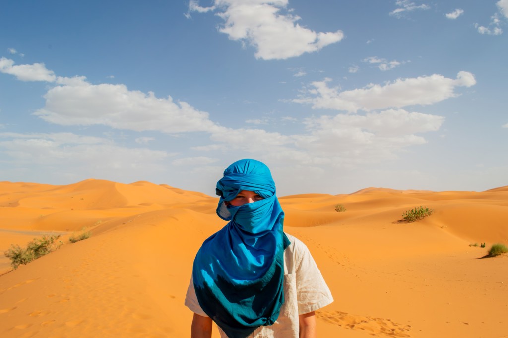 Reiziger met blauwe sjaal in de Sahara, tussen de zandduinen van Marokko.