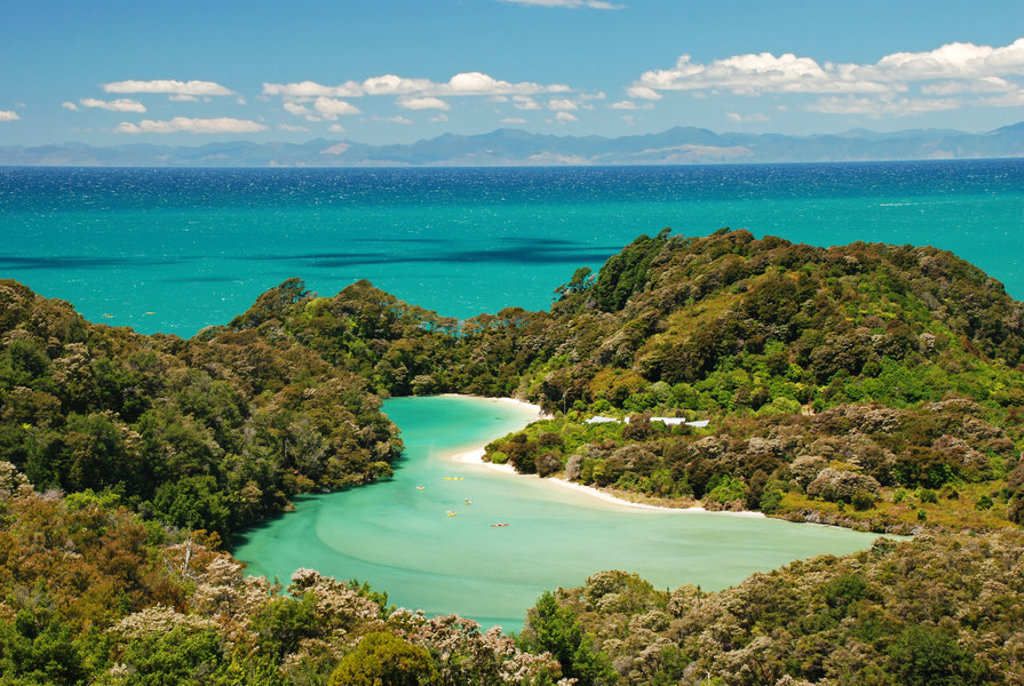 Uitzicht op turquoise baai met strand en groene heuvels in Nieuw-Zeeland tijdens groepsrondreis Australië & Nieuw-Zeeland.
