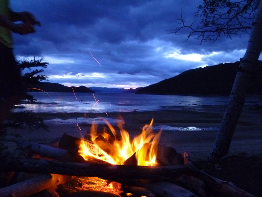 Kampvuur aan het strand bij zonsondergang tijdens familiereis Canada West in de Rockies.
