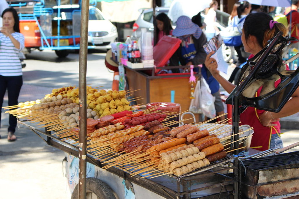 Straatkraam met Thaise snacks en satéspiezen op een markt in Thailand tijdens een familiereis.