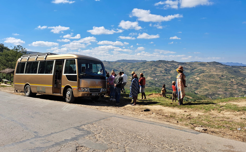 Groepsrondreis Madagascar: busstop met reizigers bij uitzichtpunt over terrassen en heuvels.