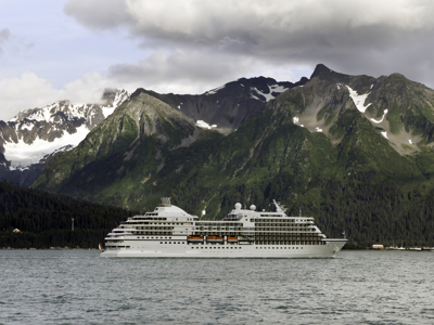 Cruiseschip voor groene bergen met sneeuwtoppen aan de kust van Oman tijdens de route Oman en Dubai.