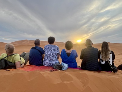 Reizigers kijken naar de zonsondergang in de Sahara bij Merzouga tijdens de Route Marokko.