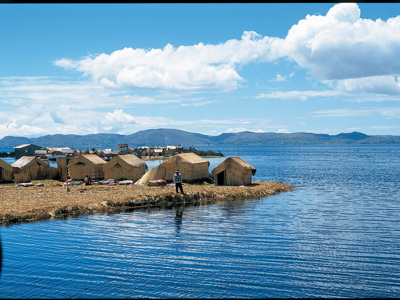Rieten huizen op de drijvende eilanden van het Titicacameer in Peru, met bergen op de achtergrond.