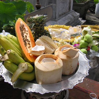 Fruitoffers met kokosnoten, bananen, papaja en ananas bij een tempel in Chiang Mai.
