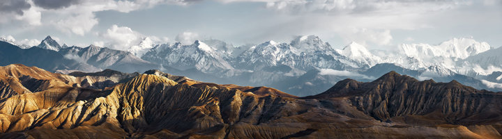 Panorama van het Himalaya-gebergte in Nepal met besneeuwde bergtoppen en ruige heuvels op de voorgrond.