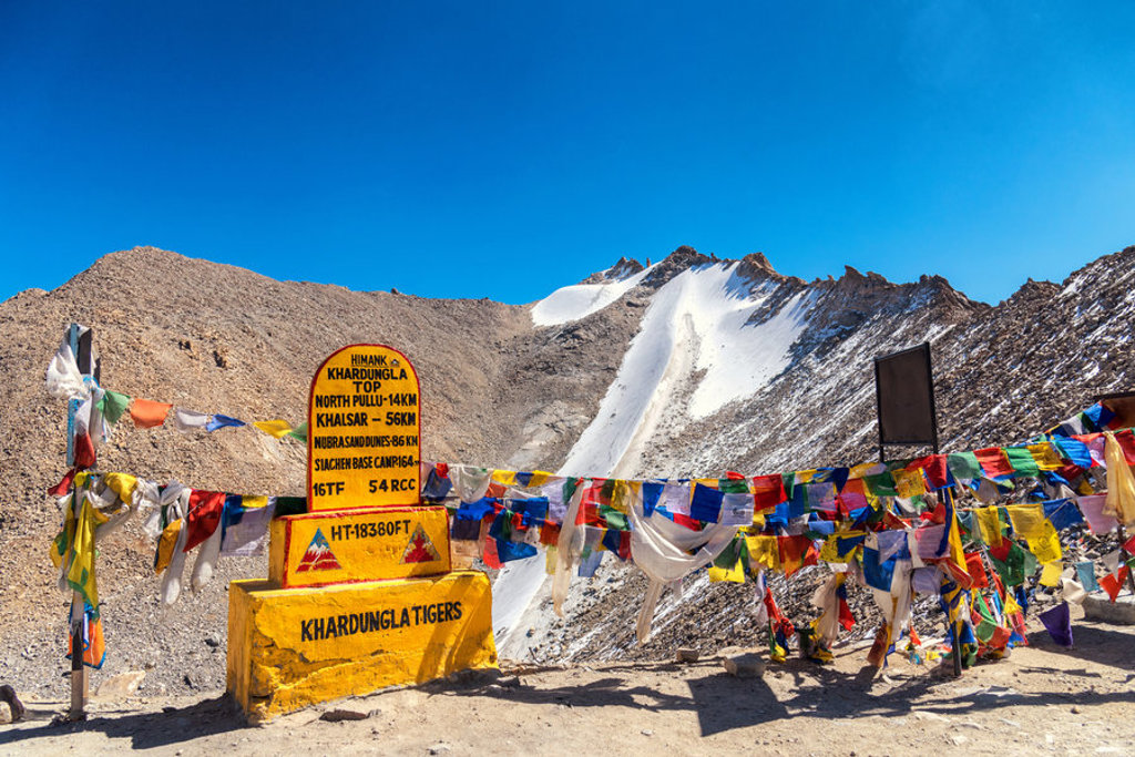 Khardung La bergpas in Ladakh met kleurrijke gebedsvlaggen en besneeuwde bergtoppen.
