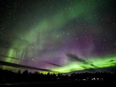 Noorderlicht boven Noord-IJsland met groene en paarse lichtgloed in een sterrenhemel.