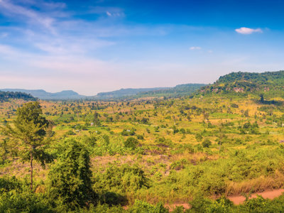 Groen heuvellandschap langs de Route Indochina, met uitgestrekte valleien onder een blauwe lucht.