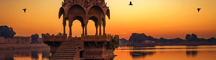Zonsondergang bij een cenotaaf aan het Gadisar-meer in Jaisalmer, Rajasthan.