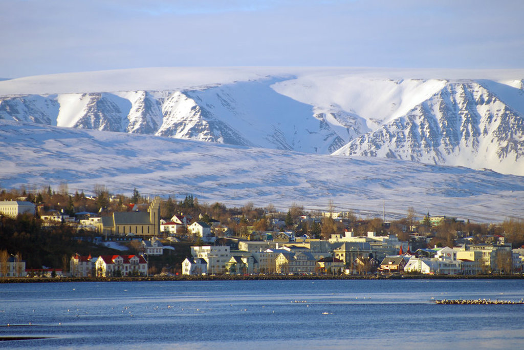Uitzicht op Akureyri aan de fjord met besneeuwde bergen op de achtergrond, Noord-IJsland.