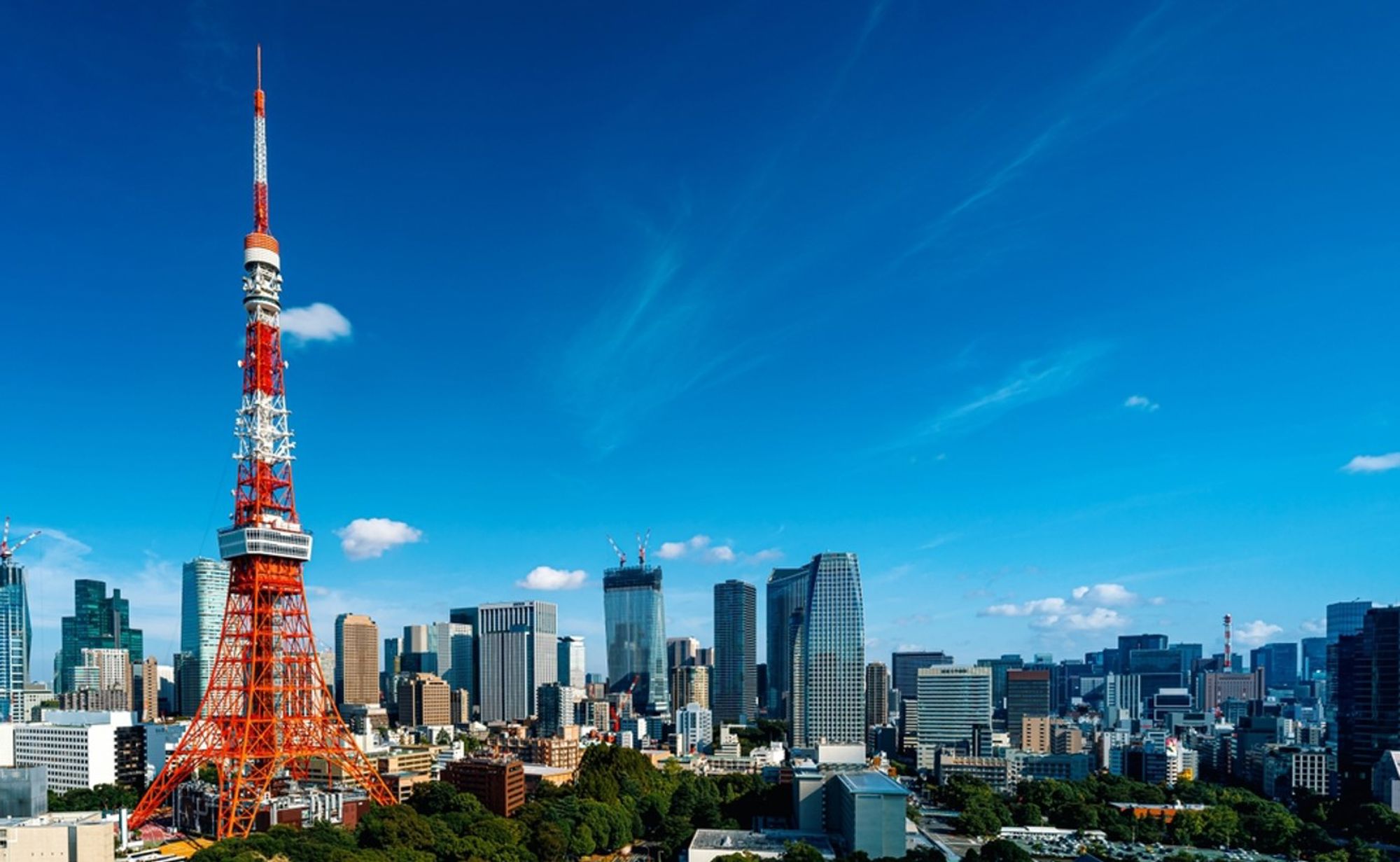 Tokyo Tower met skyline van Tokio onder een heldere blauwe lucht.