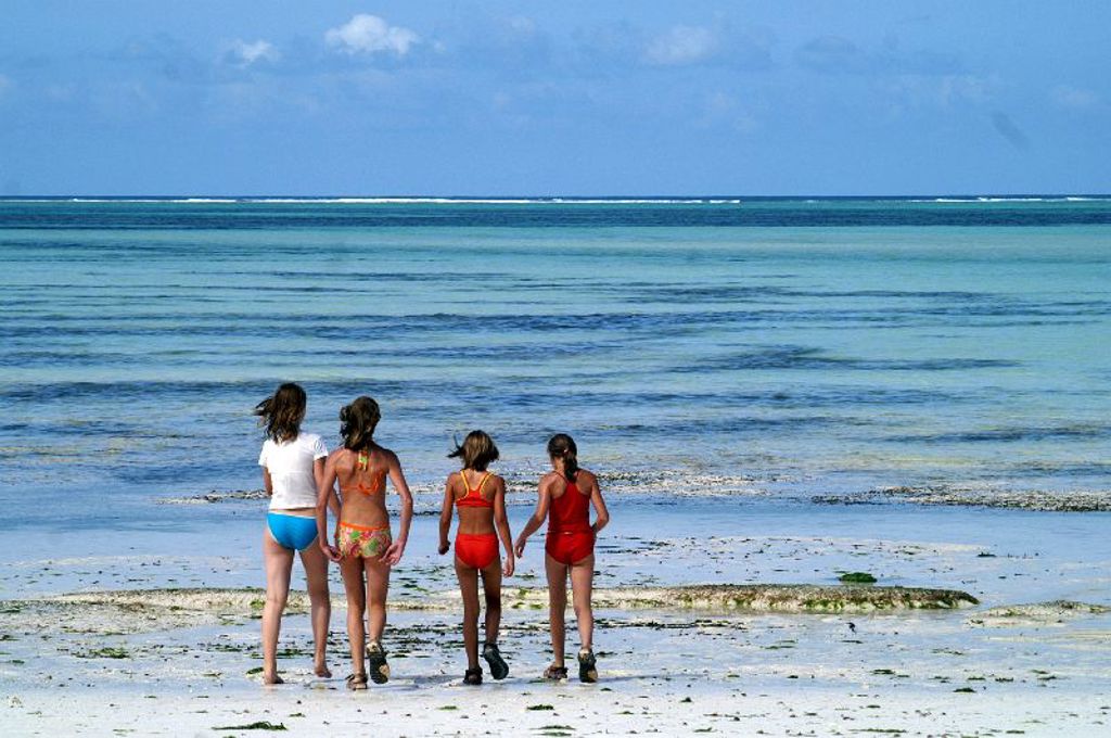 Kinderen wandelen langs het strand aan zee tijdens familiereis Kenia, Tanzania en Zanzibar.