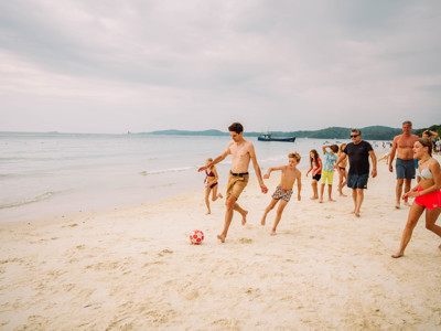 Gezin speelt voetbal op het strand tijdens de Route Thailand Noord en Zuid.