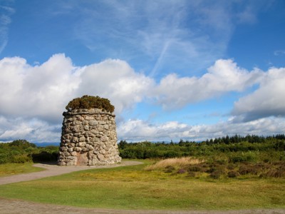 Stone cairn in de Schotse Hooglanden langs de Route Schotland, met heide en wolkenlucht.