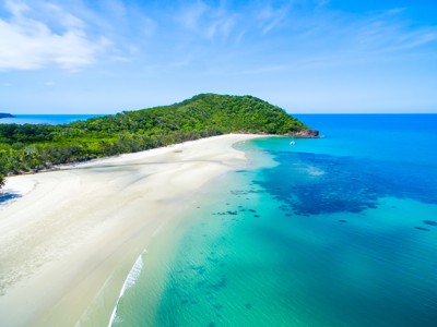Wit zandstrand en turquoise zee bij een groen eiland aan de kust van Australië.