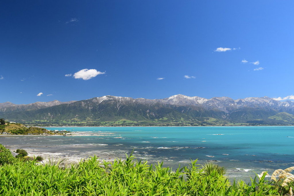 Turquoise kustlijn met bergen op de achtergrond in Nieuw-Zeeland tijdens een groepsrondreis Australië & Nieuw-Zeeland.