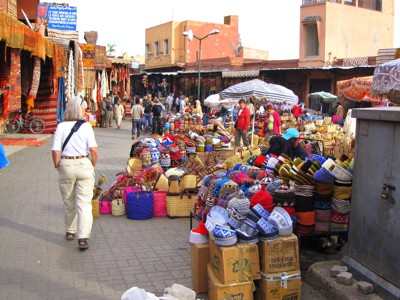 Drukke souk in Marokko met kleurrijke manden, tapijten en mutsen langs de straat.