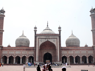 Jama Masjid-moskee in Delhi met drie koepels en minaretten, met bezoekers op het plein.