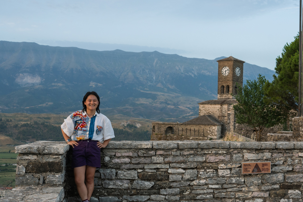 Reiziger bij de klokkentoren van Gjirokastër met bergen op de achtergrond tijdens 22-35ers reis Albanië.