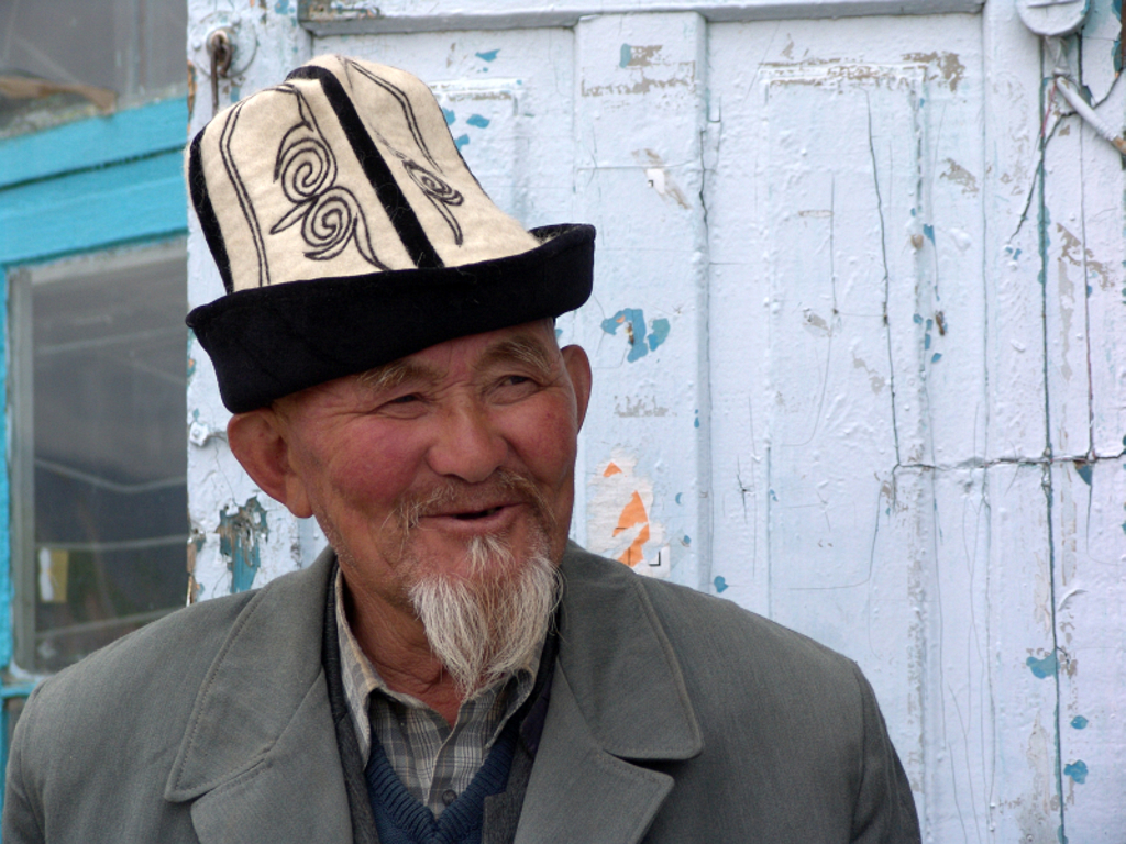 Portret van een man met traditionele vilten hoed tijdens een groepsrondreis in Kirgistan (Kirgizië).