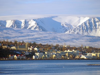 Uitzicht op Akureyri aan de fjord met besneeuwde bergen op de achtergrond, Noord-IJsland.