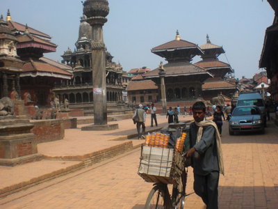 Durbar Square in Kathmandu met tempels en een straatverkoper met fiets.