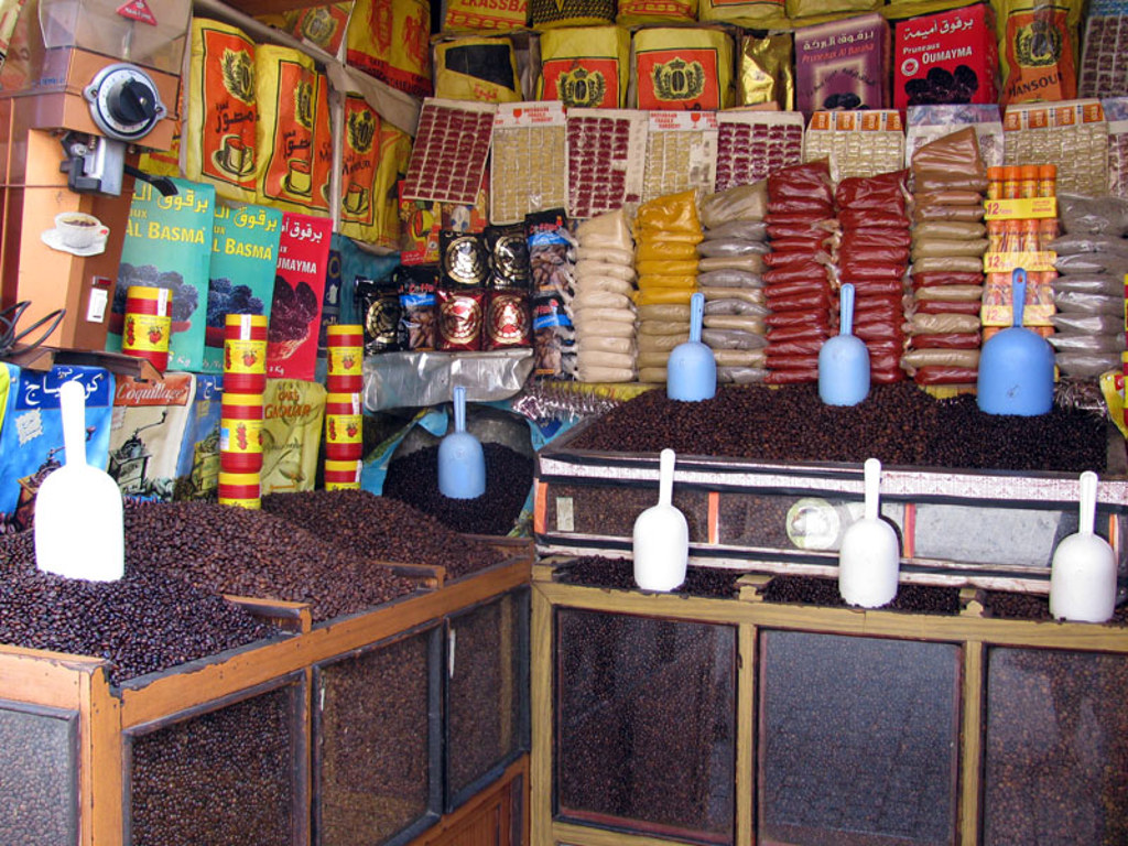 Kruiden- en koffiestand op een Marokkaanse markt, met zakken specerijen en scheppen koffiebonen.