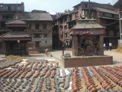Traditioneel plein in Bhaktapur, Nepal, met tempels en aardewerk dat in de zon droogt.