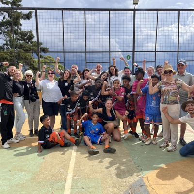 Groepsfoto tijdens familiereis Colombia met reizigers en lokale jeugd na een sportwedstrijd op een veld.