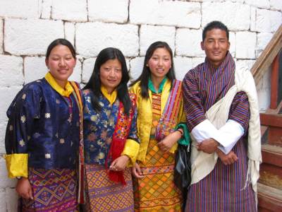 Groep locals in traditionele Bhutanese kleding bij een witstenen muur tijdens de route Sikkim en Bhutan.