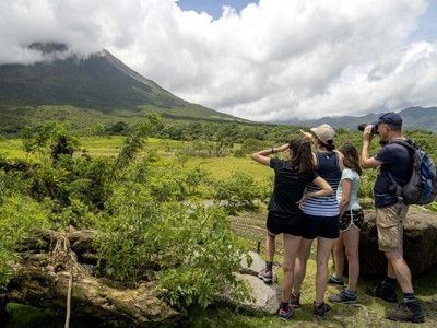 Wandelaars kijken uit over de Arenal-vulkaan en groene vallei tijdens de Route Costa Rica.