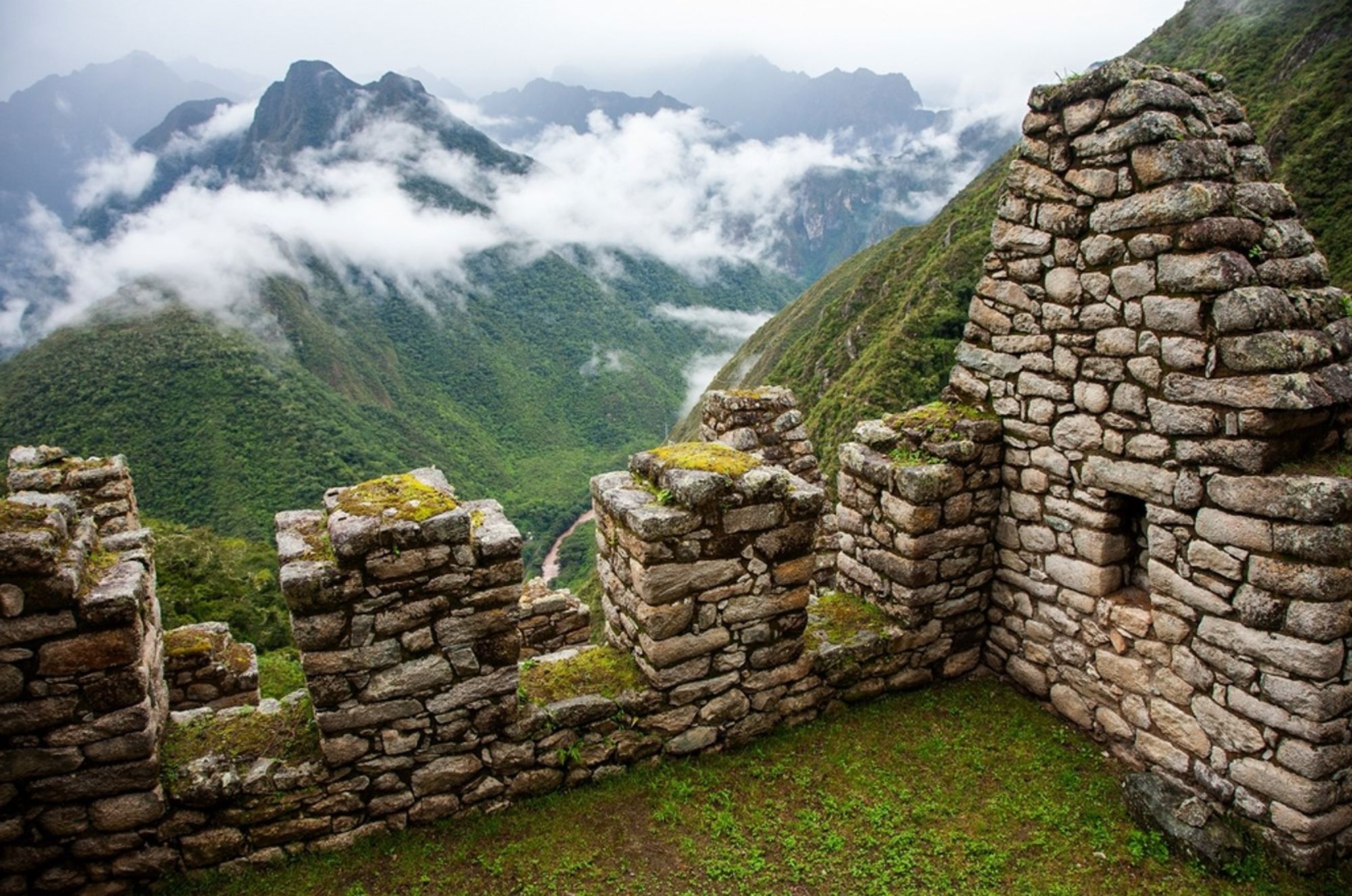 Uitzicht vanaf Machu Picchu op de Andesbergen met nevel en Inca-stenen muren in Peru.