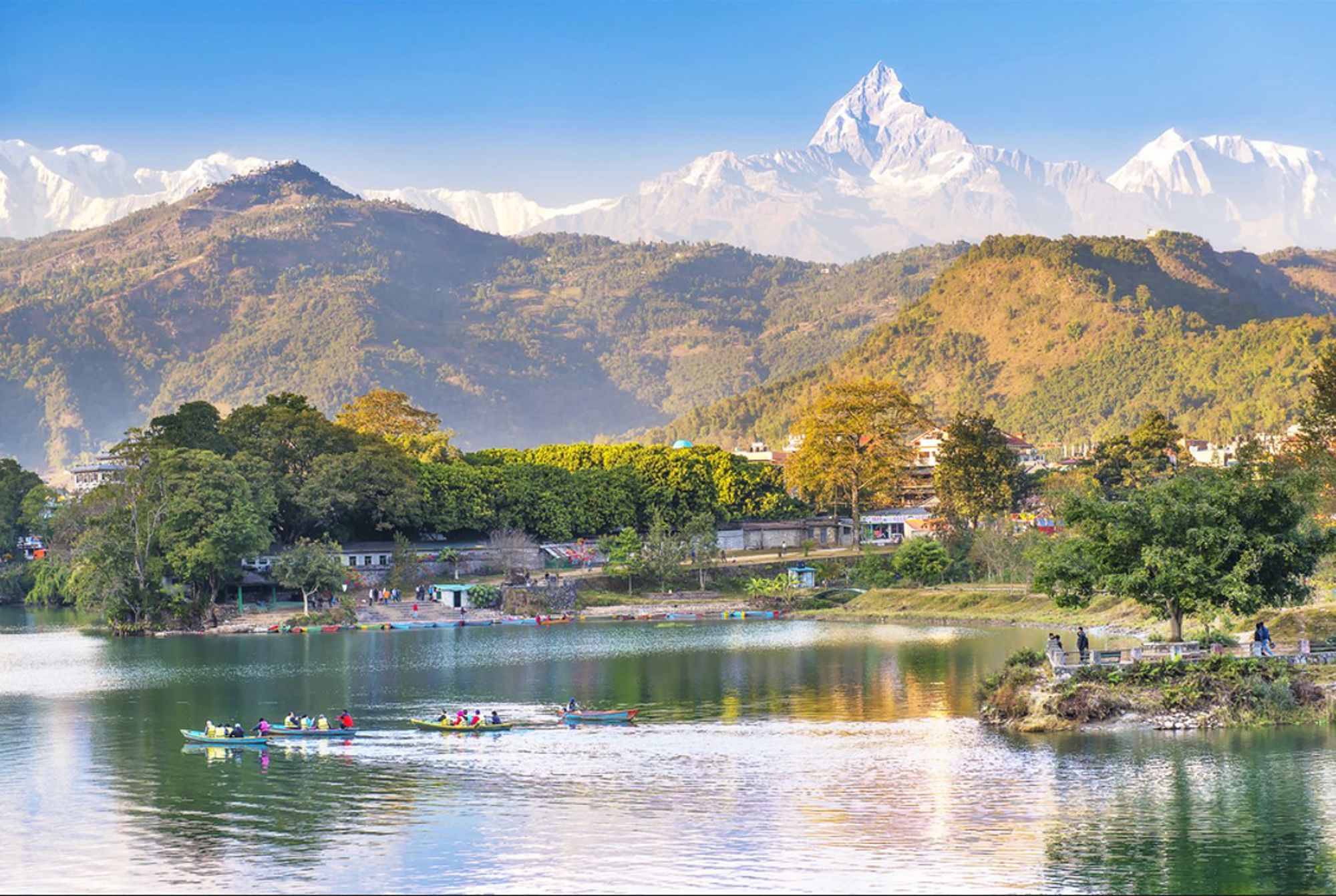 Phewa Lake in Pokhara met roeiboten en uitzicht op de Annapurna-bergen in Nepal.