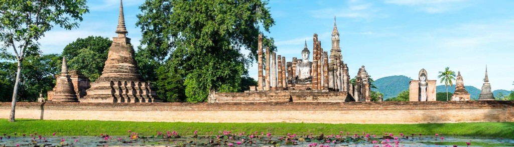 Ruïnes van Sukhothai Historical Park met Boeddhabeelden en lotusvijver, hoogtepunten van Thailand.