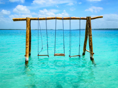 Houten schommel in turquoise zee bij Mexico, ideaal voor een familiereis langs de kust.