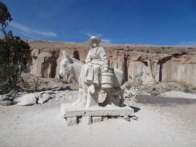 Wit stenen beeld van een man op een ezel in een steengroeve in Peru, Route Peru dag 6.