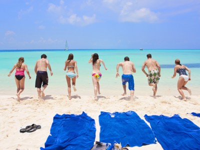Reizigers rennen het turquoise zeewater in vanaf een wit zandstrand tijdens Route Mexico.