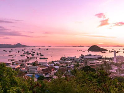Uitzicht op de haven van Labuan Bajo bij zonsondergang, met vissersboten en een vuurtoren op Flores.
