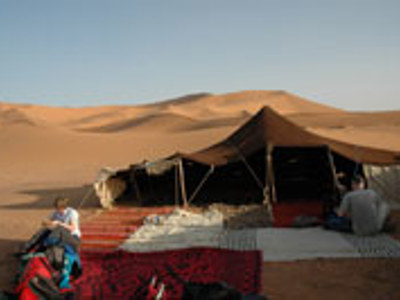 Woestijnkamp met tent en tapijten tussen de zandduinen in Marokko.