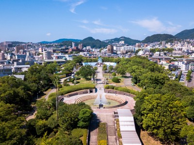 Uitzicht over het Vredespark in Nagasaki met fontein en stadslandschap op de achtergrond.