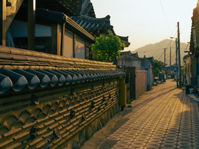 Rustige straat met traditionele hanokhuizen en stenen muur in Zuid-Korea tijdens zonsondergang.