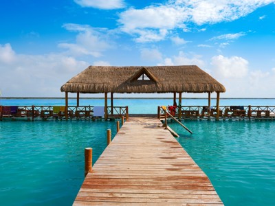 Houten pier met rieten paviljoen aan een turquoise lagune op de Route Ruta Maya.