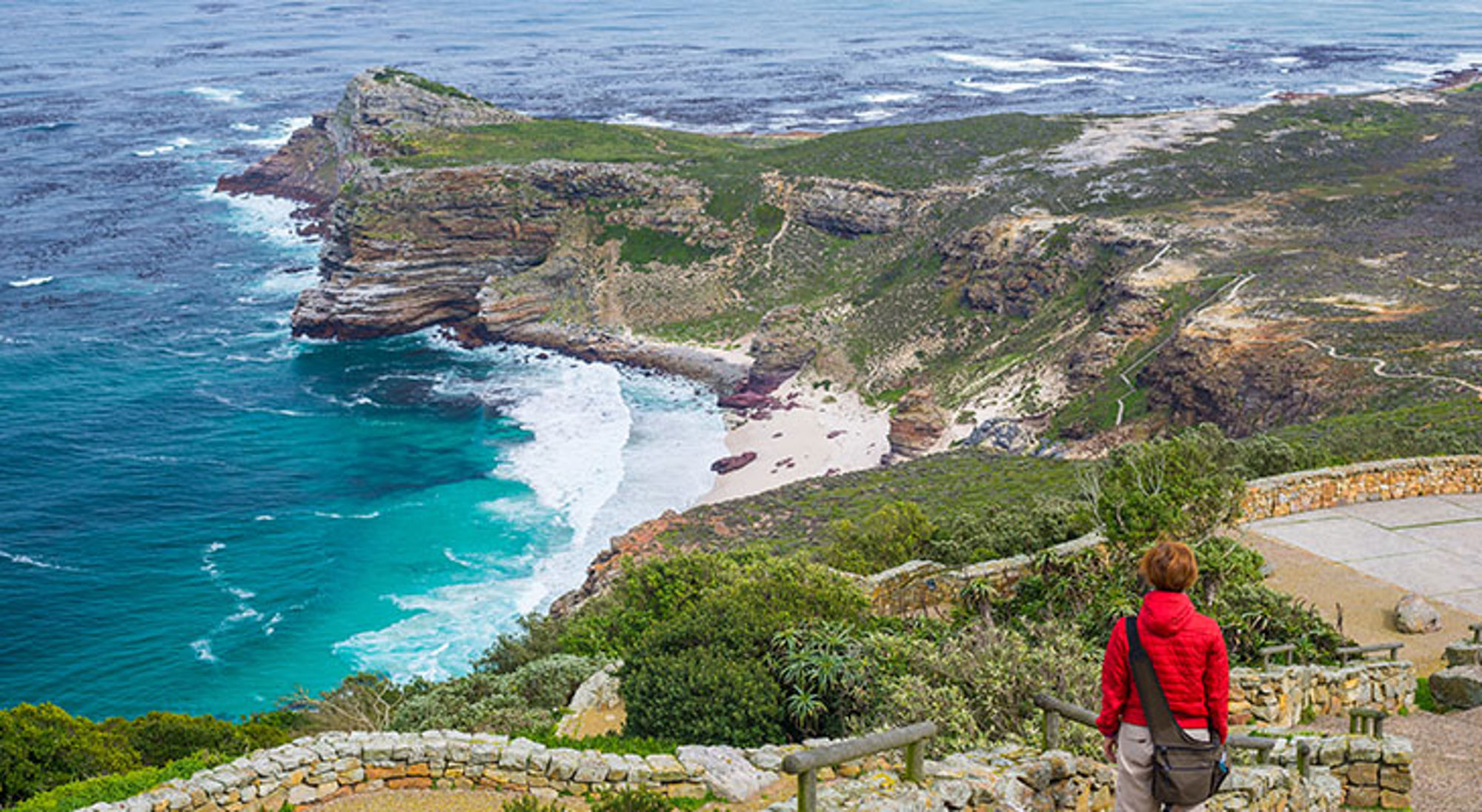 Uitzicht op Kaap de Goede Hoop met ruige kliffen, turquoise zee en wandelpad langs de kust in Zuid-Afrika.