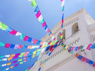 Kleurrijke papel picado-slingers voor een witte kerk in Mexico, tijdens de Route Mexico 21 dagen.