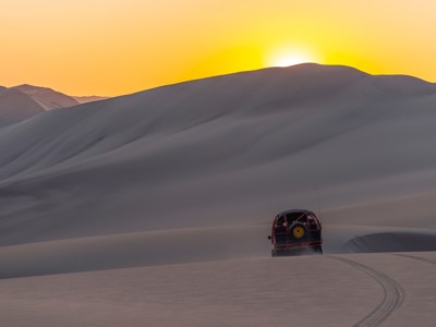 Dune buggy rijdt door de zandduinen van Huacachina bij zonsondergang, Peru.