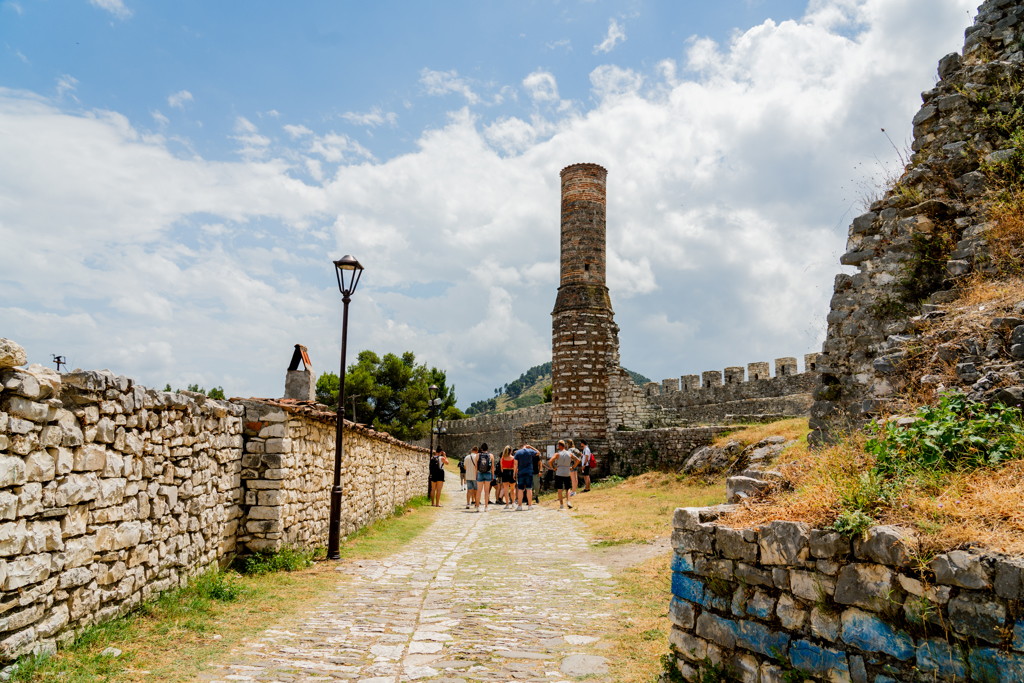 Wandeling met groep langs de kasteelmuren van Berat, Albanië, met uitzicht op de citadel en toren.